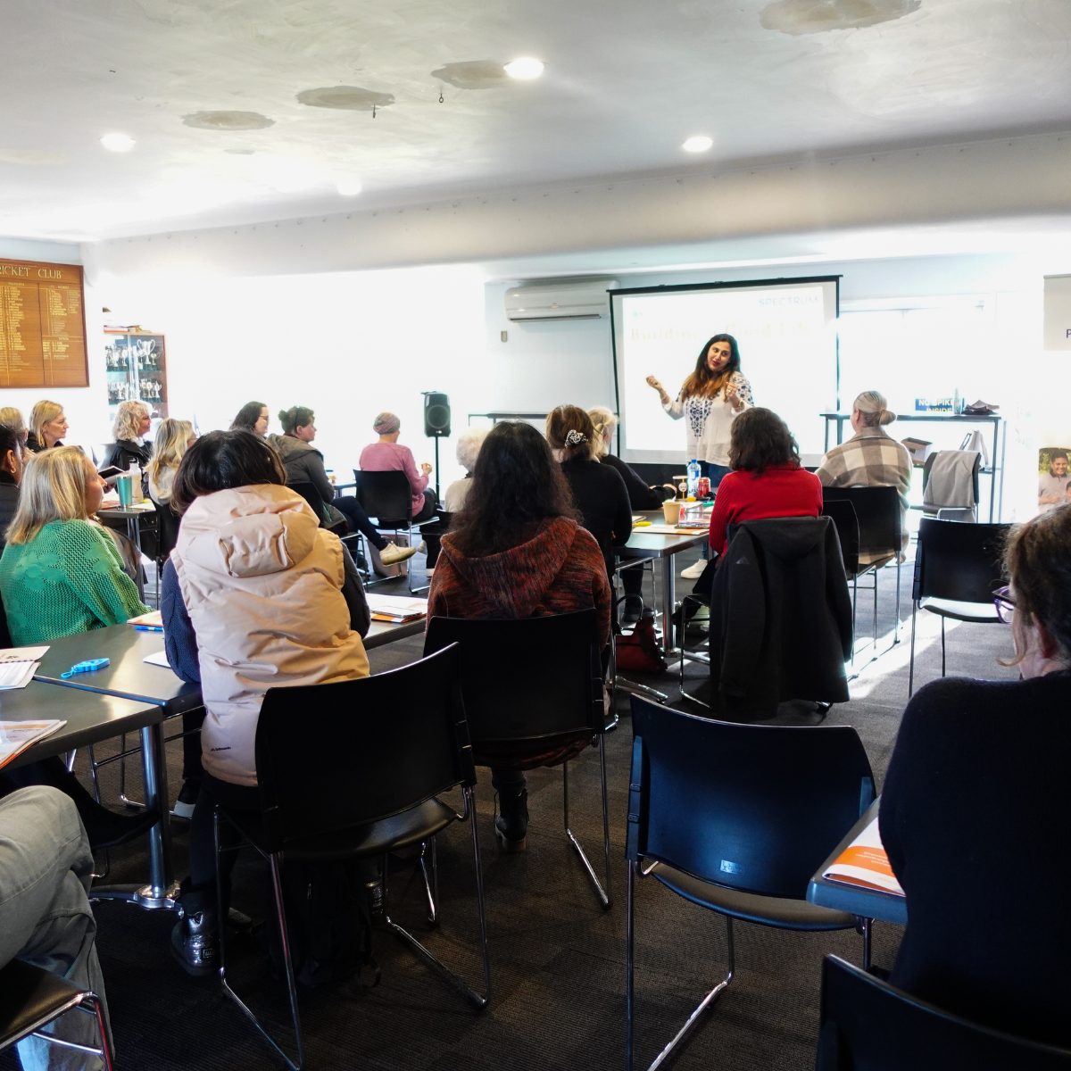 Woman presents at the front of the room to a seated crowd.
