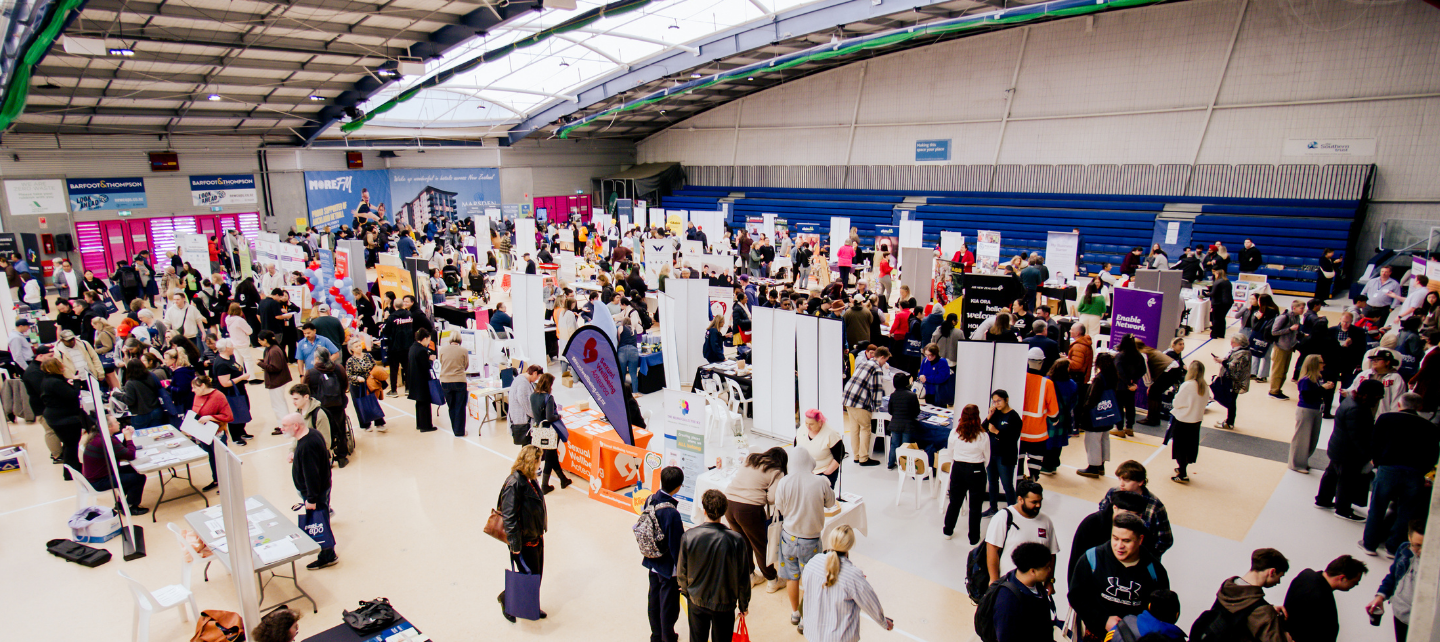 A wide shot of the Transition Expo with lots of stalls and people.